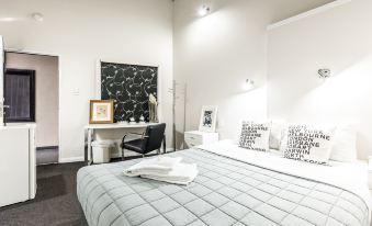 a modern bedroom with white walls , black and white striped walls , and a large bed with a gray comforter at Airport Hotel Sydney