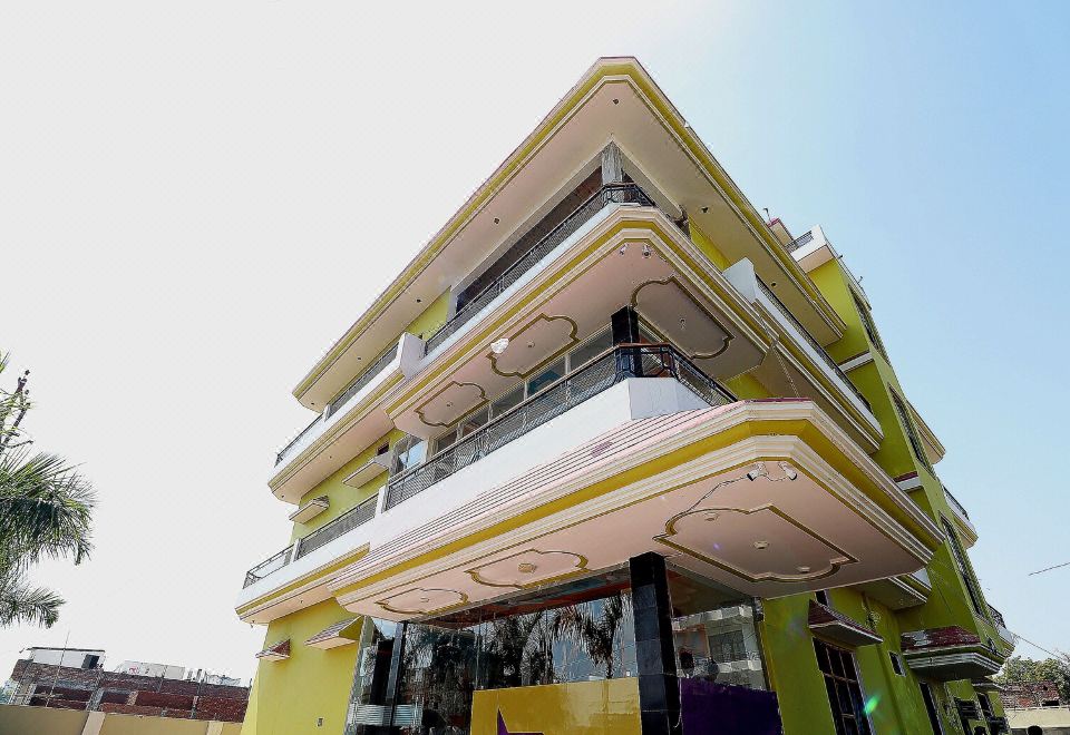 a yellow and white building with a balcony on each floor , surrounded by green trees at Collection O 27949 Hotel Kriti Green