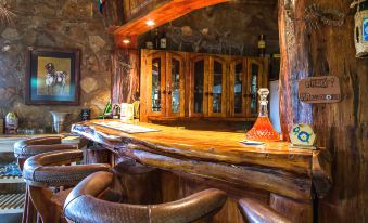 a bar with a wooden countertop and brown leather chairs , featuring a red glass bottle on the counter at Morning Glory Cottages