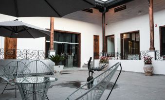 a courtyard with a variety of chairs and tables , some of which are covered with a black and white striped tablecloth at Casa San Miguel Hotel Boutique y Spa