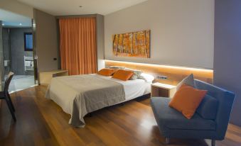 a hotel room with a king - sized bed , a couch , and a painting on the wall at Hotel America Igualada