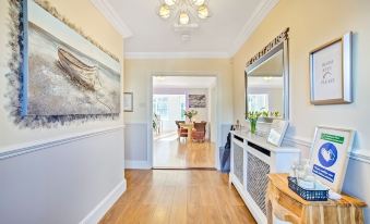 a foyer with a wooden floor , a white cabinet , and a painting on the wall at The Coast House B&B