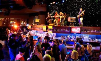 a lively bar scene with a band playing on stage , surrounded by a crowd of people at Cherokee Casino West Siloam Springs Resort