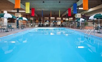 a large indoor swimming pool surrounded by lounge chairs and umbrellas , providing a relaxing atmosphere at Ramada by Wyndham Uniontown