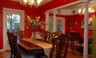 a dining room with a wooden table , chairs , and a chandelier hanging from the ceiling at Sabal Palm House Bed and Breakfast