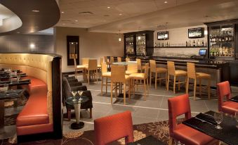 a restaurant with a bar and dining area , featuring several chairs and tables arranged around it at DoubleTree by Hilton Pittsburgh Monroeville Convention Center