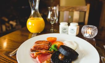 a plate of food with sausages , tomatoes , and a side of mushrooms is displayed on a table at Recruiting Sergeant