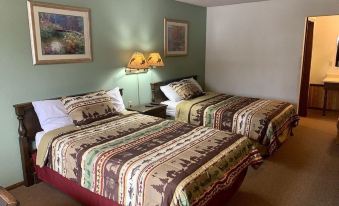 a hotel room with two beds , each covered in a bed spread featuring various patterns and designs , along with lamps on either side of the bed at Hidden Lake Resort