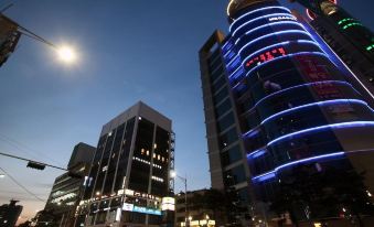 A city at night with buildings illuminated in blue and white colors on both sides at KSTAR METRO Hotel