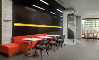 a modern dining area with black and white checkered tablecloths , red benches , and black chairs at Hyatt Centric Arlington