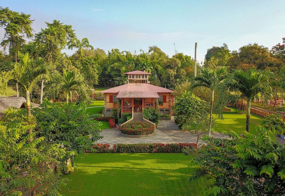 a beautiful garden with lush greenery , a wooden gazebo , and a fountain in the center at Hacienda la Danesa
