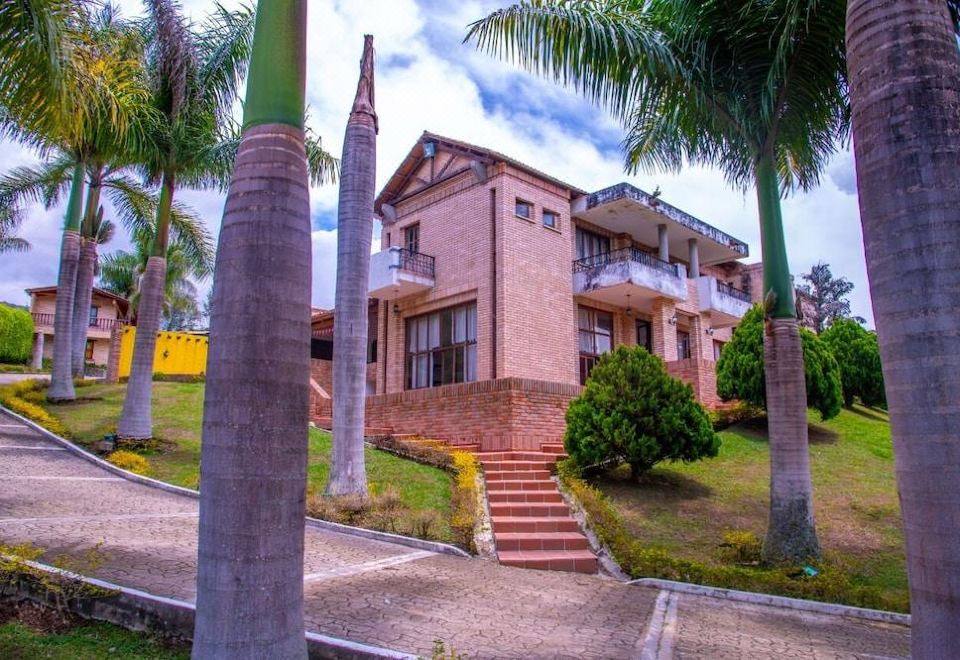 a large brick house situated on a hillside , surrounded by palm trees and overlooking a body of water at Hotel la Perla
