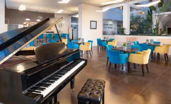 a large , black piano in the middle of a restaurant , surrounded by chairs and tables at Hotel Olympia