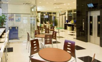 a modern cafeteria with wooden tables and chairs , black and white flooring , and large windows at Toyoko Inn Shizuoka Fujieda Eki Kita Guchi