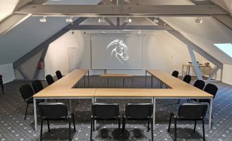 a conference room with a large table and chairs , white walls , and a projection screen on the wall at Logis Hotel Restaurant de l'Abbaye