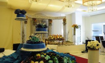 a room with a blue cake on top of a table , surrounded by potted plants and flowers at Hotel Venezia