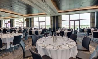 a large banquet hall with numerous round tables and chairs , all set for a formal event at Hilton Garden Inn Doncaster Racecourse