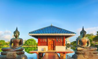 a traditional chinese building with a blue roof and red walls , surrounded by water and two stone statues at Capital Villa