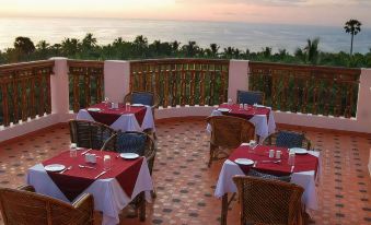 a dining room with tables and chairs set up for a meal , overlooking the ocean at Somatheeram Ayurveda Village
