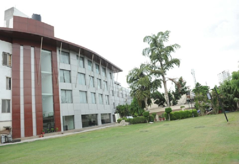 a large building with a red roof and white windows is surrounded by green grass and trees at Hotel La