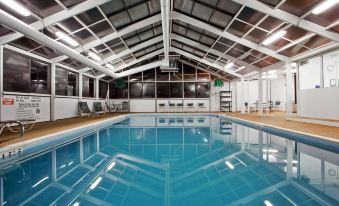 an indoor swimming pool surrounded by a gymnasium , with several people gathered around the pool at DoubleTree by Hilton Richmond - Midlothian