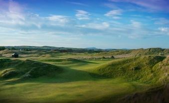 a panoramic view of a green landscape with dunes and mountains under a blue sky at Flynns of Termonfeckin Boutique Hotel