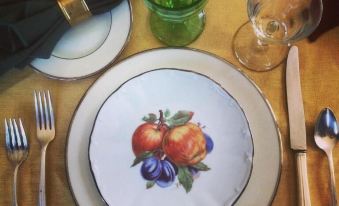 a dining table set with a white plate , silverware , and various fruits on the plate at The White House Inn