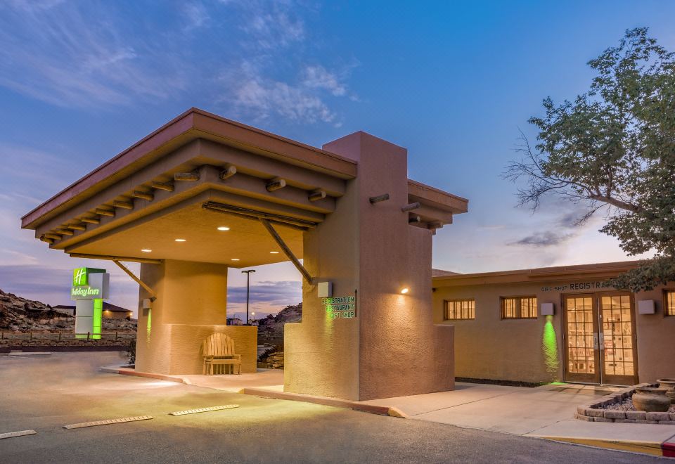 a building with a green door is lit up at night , and trees surrounding it at Holiday Inn Canyon de Chelly (Chinle)