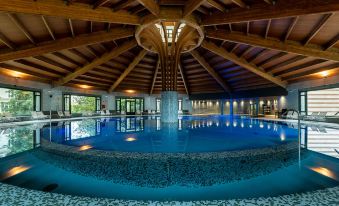 a large , circular pool with a wooden roof structure is surrounded by several blue and white mosaic tiles at Castilla Termal Solares