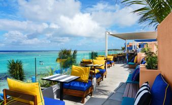 a rooftop patio with a view of the ocean , featuring blue and yellow chairs and umbrellas at Salt of Palmar, Mauritius