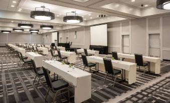 a conference room with white tables and black chairs , a large screen on the wall , and multiple screens hanging from the ceiling at Tysons Corner Marriott