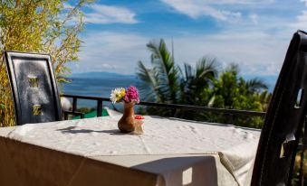 a table with a vase of flowers on it , situated on a balcony overlooking the ocean at Belvedere Hotel