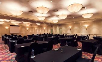 A spacious room with neatly arranged rows of black chairs is prepared for an event at the hotel at Carnival City Hotel