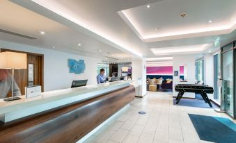 a modern hotel lobby with a wooden reception desk , multiple seating areas , and a pool table at Holiday Inn Express Burnley M65, Jct.10