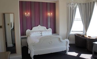 a white bed with a white headboard and footboard is in a room with purple curtains at Atlanta