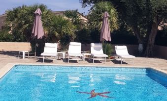 a swimming pool with umbrellas and lounge chairs surrounding it , as well as a red starfish on the surface at Stella Marina