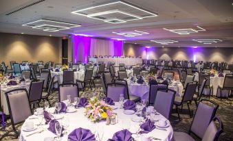a large banquet hall with multiple tables set up for a formal event , complete with purple and white tablecloths , napkins , and at DoubleTree by Hilton Hotel Syracuse