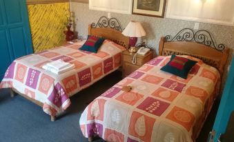 a room with two beds , each made up with a quilt and pillows , is decorated with a colorful flower design at Grand Hotel