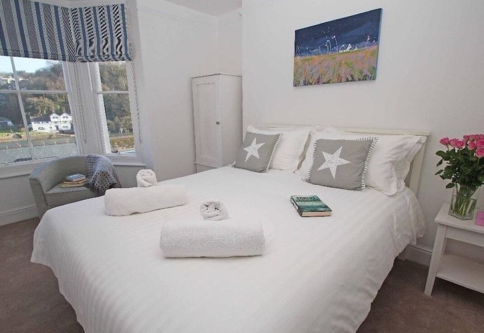 a white bedroom with a large bed , a nightstand , and a painting on the wall at Panacea
