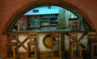 a rustic bar with wooden stools and an arched opening , providing a view of the surrounding area at Orion Hotel