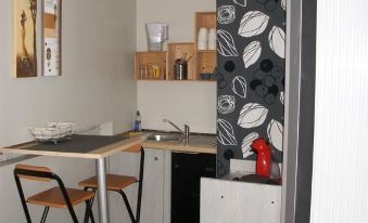a small kitchen with a dining table and chairs , as well as a refrigerator and microwave at Cleome