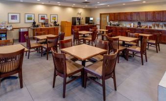 a restaurant with wooden tables and chairs , a kitchen area , and a bar counter at Country Inn & Suites by Radisson, Princeton, WV