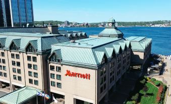 a large hotel building with a marriott sign on the front , surrounded by water and mountains in the background at Halifax Marriott Harbourfront Hotel