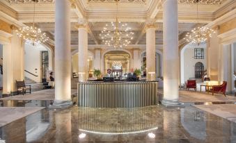 a grand hotel lobby with a marble floor and a large reception desk in the center at Grand Hotel Et des Palmes