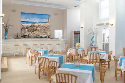 a large dining room with multiple tables and chairs , a bar , and a painting on the wall at Hotel Summery