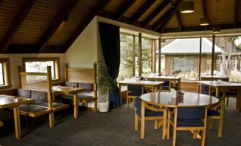 a dining area with wooden tables and chairs , as well as a window overlooking a beautiful landscape at Alpine Lodge