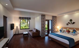 a hotel room with a king - sized bed , a flat - screen tv , and a door leading to a patio area at Holiday Inn Resort Goa