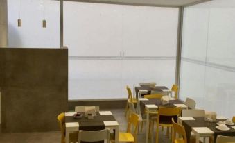 a modern dining area with tables and chairs , large windows , and a view of the city at Hotel Artemide