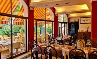 a restaurant with several tables and chairs , all set for dining , is visible through a large window at Aparthotel Ona Cala Pi Club