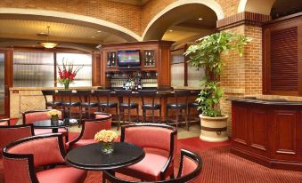 a modern bar with red chairs , wooden furniture , and a tv screen on the wall at Ameristar Casino Hotel Council Bluffs